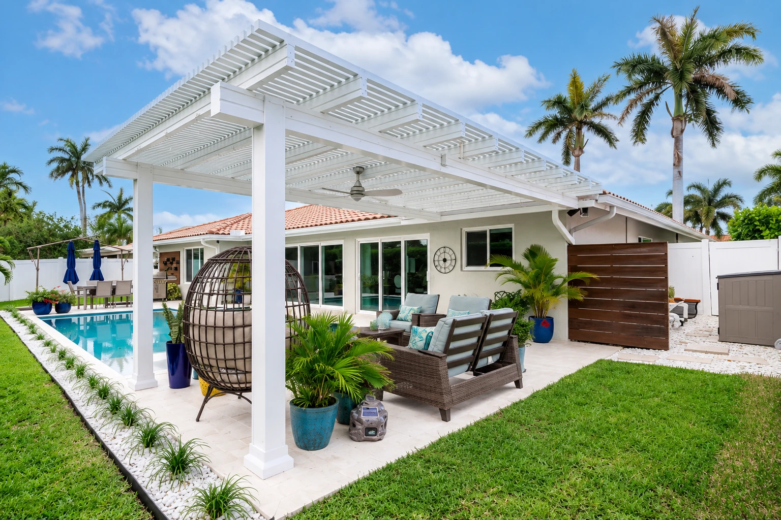 White pergola-style patio cover shading an outdoor seating area beside a swimming pool.