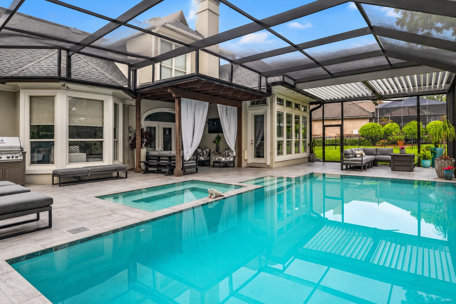 Screened patio enclosure around a swimming pool, with a dark overhead frame and outdoor seating.